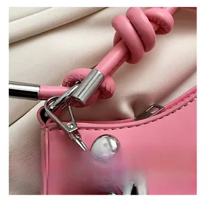 Detail view of pink leather bag with knotted handle and silver heart charm pendant