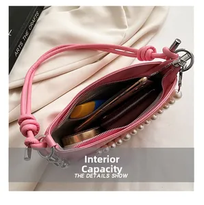 Detailed interior view of a pink shoulder bag with pearl chain and daily essentials