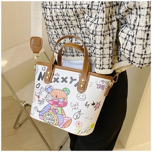 Detail der weißen Graffiti-Tragetasche mit Cartoon-Bär-Print und braunen Ledergriffen
