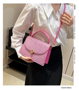 Detail of pink sequin crossbody bag with gold twist lock shown on a white shirt background