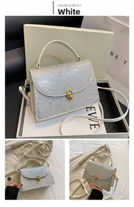 Detail of silver glitter crossbody bag with gold metallic lock and gift box packaging