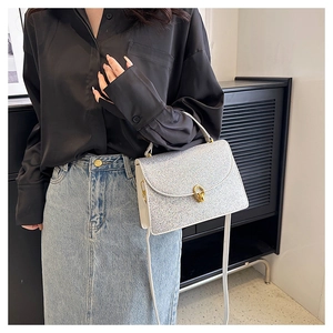 Detail of silver glitter crossbody bag with gold metallic twist lock and top handle