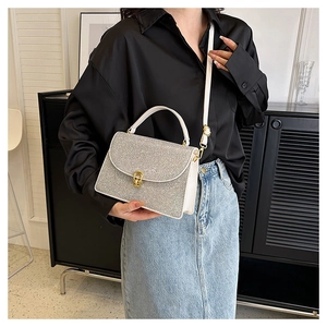 Detail of glittery silver crossbody bag with gold twist lock and white leather strap