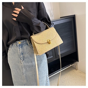 Close-up of glitter sequins texture and gold rotating lock on the stylish crossbody bag