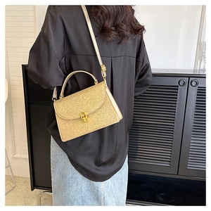 Golden sequin crossbody bag with a round rotating lock worn by a model in real life