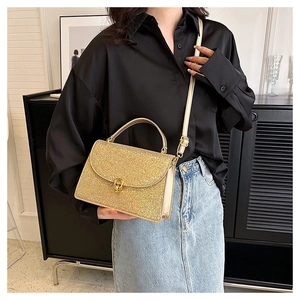 Styling of a golden sequin crossbody bag with a metallic lock on a black silk shirt