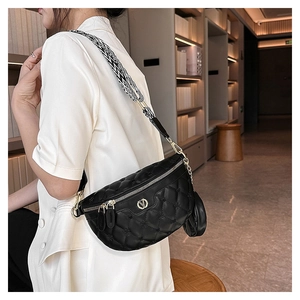 Detail der schwarzen Stepptasche mit goldenem V-Logo und geometrischem Gurtband