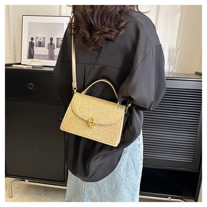 Champagne gold glitter handbag with metal lock shown in a stylish indoor setting