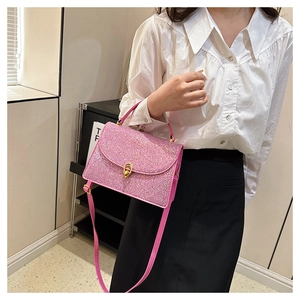 Detail of pink sequin crossbody bag featuring a gold twist lock and shimmering texture