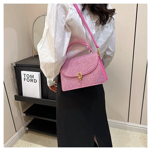 Detail of pink sequin handbag featuring a gold metallic twist lock and handle