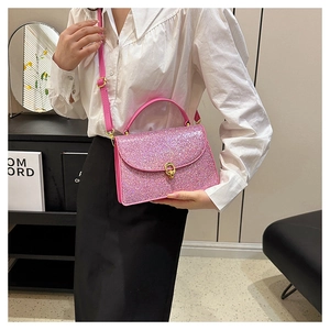 Detail of pink glitter crossbody bag featuring a gold twist lock and smooth leather handle