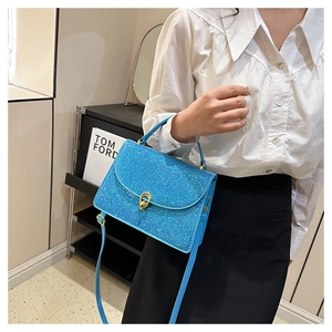 Detail of bright blue sequin crossbody bag with gold knot buckle and slender strap