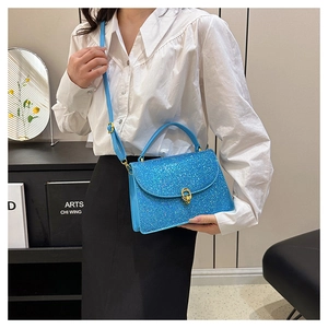 Detail of blue sequined crossbody bag featuring a golden metal clasp and chain strap