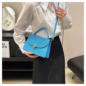 Detail of bright blue sequin crossbody bag with gold buckle on a stylish model