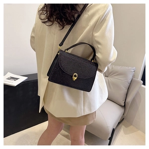 Model wearing a black glitter crossbody bag with gold hardware and stylish flap closure