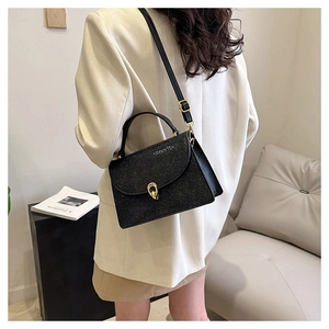 Detail of black glitter crossbody bag featuring a gold ring twist lock and textured finish