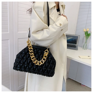 Detail of black quilted cloud bag featuring gold chain handle and modern textured finish