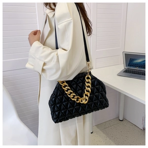 Model wearing a black quilted cloud bag featuring a chunky gold chain and pleated texture