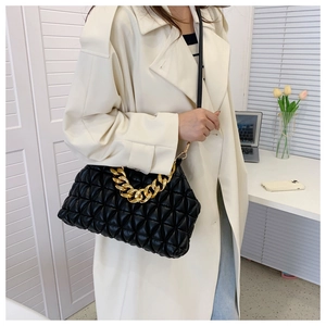 Detailed close-up of a black quilted dumpling bag with chunky gold chain and leather strap