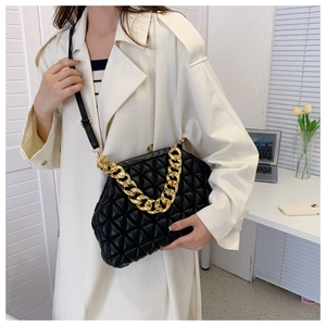 Detail of black quilted cloud bag with gold chunky chain worn with a beige coat