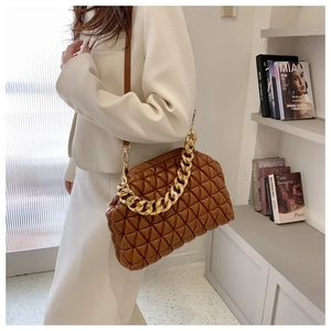 Close-up of dark brown quilted leather bag featuring a chunky gold chain and soft texture