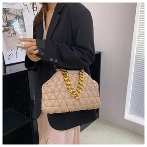 Detail of beige quilted cloud bag with thick gold chain handle on model's black suit