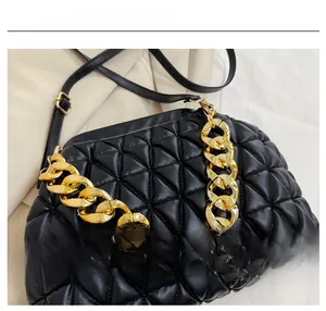 Close-up of quilted black handbag with bold golden chain strap and premium hardware