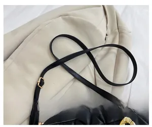 Detail view of adjustable leather strap and golden metal hook on black quilted bag
