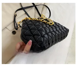 Close-up of quilted black cloud bag featuring chunky gold chain and side texture detail