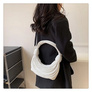 Close-up of white woven knot shoulder bag with circular rope design and hand-tied texture