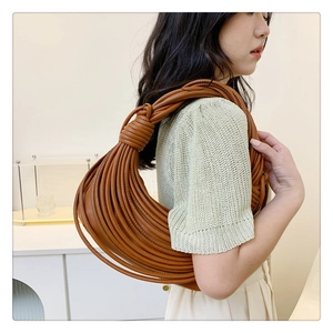 Detail of creative brown woven shoulder bag with knotted handle and leather texture