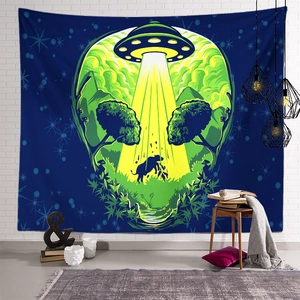 Detail of alien skull tapestry featuring UFO and cow scene on a white brick wall