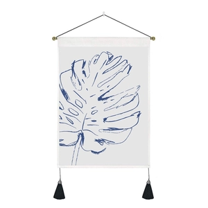Close-up of minimalist monstera leaf wall tapestry with wooden rod and black tassels