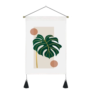 Detail of Nordic tapestry featuring green monstera leaf with wood pole and black tassels