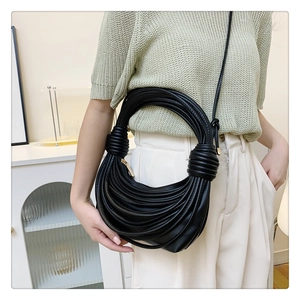 Detail of black woven knotted shoulder bag with unique layered cord texture and slim strap
