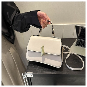Détail du sac à main en cuir PU blanc cassé avec boucle métallique dorée en forme de feuille