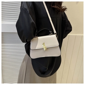 Détail d'un sac bandoulière minimaliste en cuir PU crème avec boucle métallique dorée ondulée