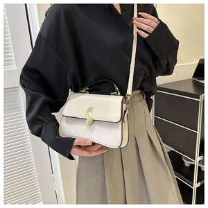 Détail du sac bandoulière crème avec boucle feuille dorée et finitions noires chic