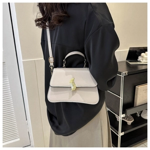 Détail du sac bandoulière beige avec fermoir feuille dorée et bord ondulé