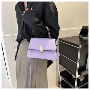 Détail d'un sac à main en cuir violet clair avec une boucle dorée abstraite