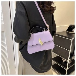 Détail du sac bandoulière lavande avec fermoir feuille dorée porté sur une tenue noire