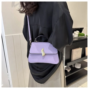 Détail du sac à main lilas avec boucle dorée ondulée et poignée supérieure ronde