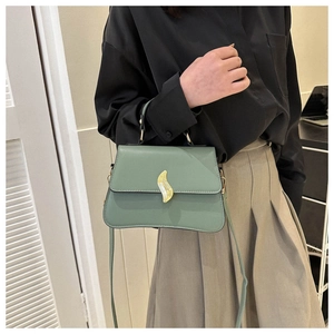 Sac bandoulière vert sauge porté avec chemise noire et jupe plissée kaki élégante