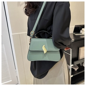 Détail du sac à main en cuir vert sauge avec boucle feuille dorée et anse ronde noire