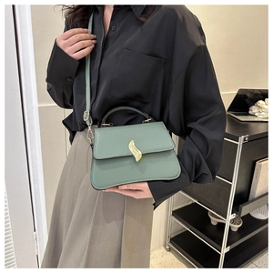 Sac bandoulière vert d'eau avec boucle feuille dorée porté par un mannequin en intérieur