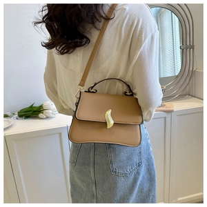 Détail du sac bandoulière marron clair avec un fermoir doré unique en forme de vague