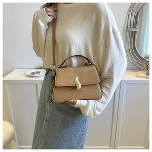 Détail du sac en cuir kaki avec fermoir métallique doré ondulé et poignée supérieure