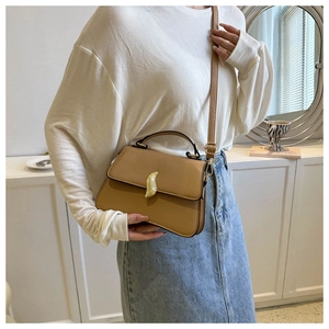 Gros plan d'un sac bandoulière marron vintage avec une boucle crochet en métal doré