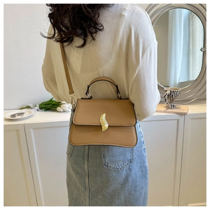 Détail du sac à main en cuir marron avec boucle dorée et bandoulière sur le mannequin