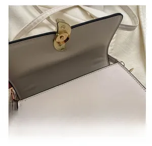Gros plan détaillé de la boucle magnétique dorée sur le sac bandoulière en cuir PU beige